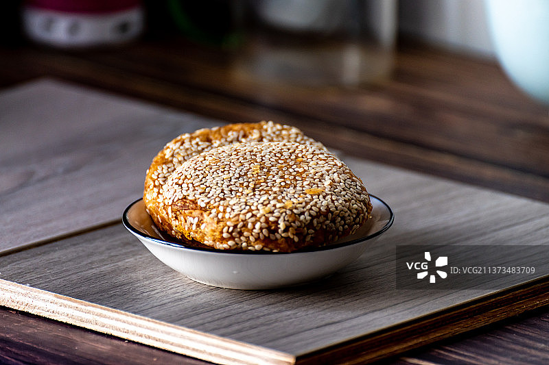 老北京特色面食小吃麻酱饼麻酱烧饼.放在桌子上盘子里的麻酱烧饼图片素材