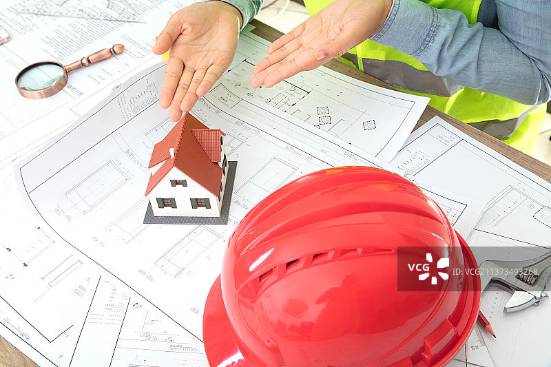 双手指着图纸上的小房子模型图片素材