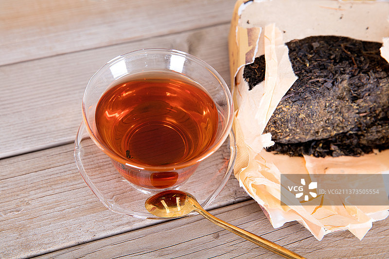 一碗茶水和半块黑茶茶砖及一个小勺子图片素材