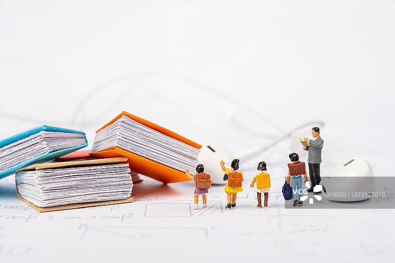 微缩景观老师在草稿纸上教导学生学习知识旁边放着耳机图片素材