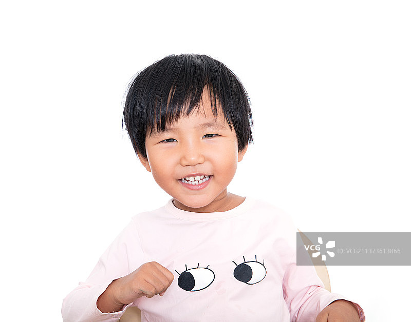 白背景前坐在椅子上满面微笑看着镜头的小女孩图片素材
