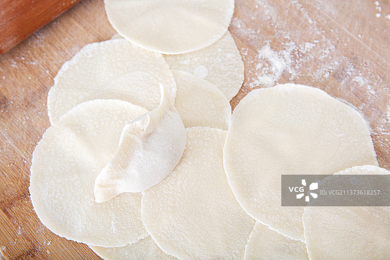 砧板上大量饺子皮和一个包好的饺子图片素材