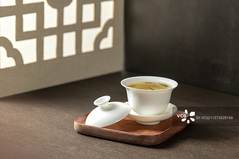 盖碗茶三才杯摆放在窗棂影木桌面上图片素材