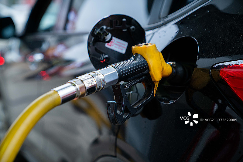 手动加油的汽车与燃料，特写，泵设备的汽油在加油站。图片素材