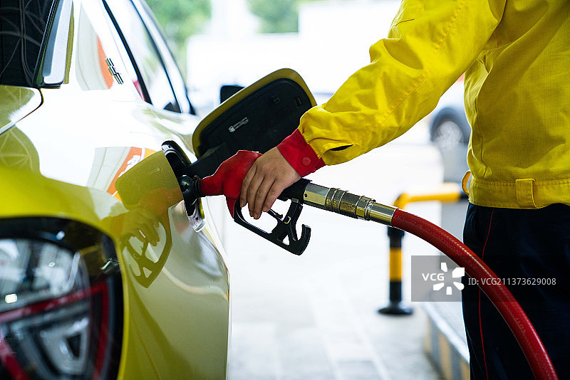 手动加油的汽车与燃料，特写，泵设备的汽油在加油站。图片素材