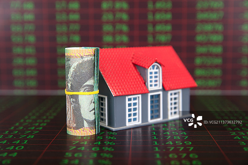 金融数据背景上一卷澳元纸币和一个小房子模型图片素材