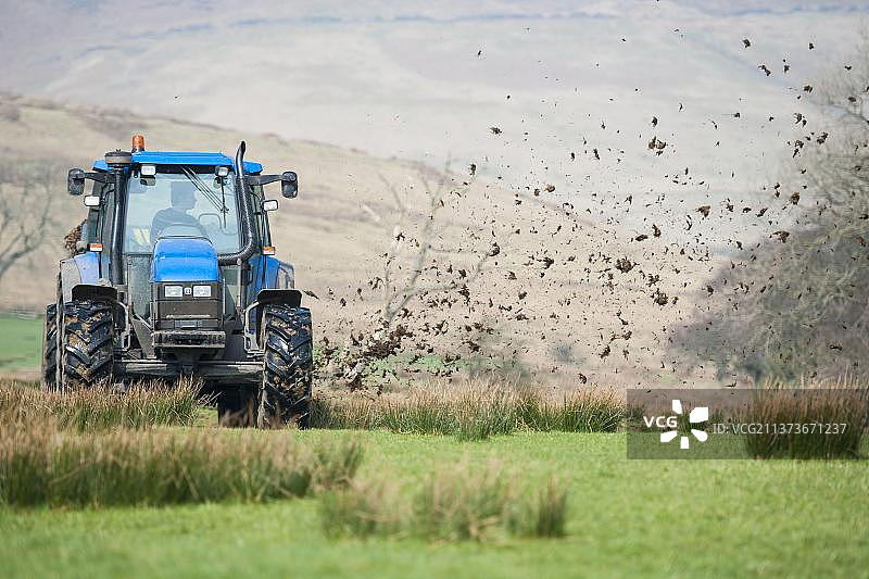 新荷兰TS115拖拉机在英国兰开夏郡的草地上撒粪图片素材