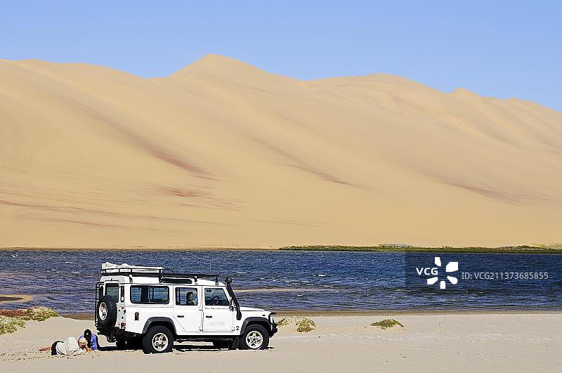 在纳米比亚纳米布沙漠的湿地中驾驶路虎卫士越野车的男人们图片素材