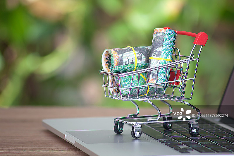 桌子上的电脑键盘上一辆装满澳元钞票的购物车图片素材