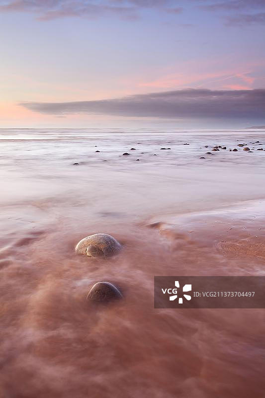 英国北德文Westward Ho!海滩上的鹅卵石与日落时分的涨潮图片素材