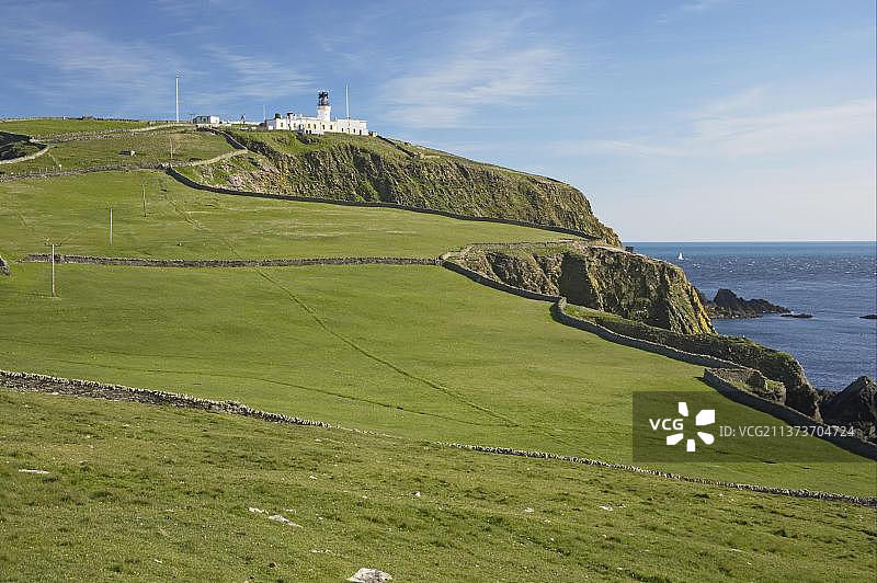 设得兰群岛悬崖牧场与远方灯塔图片素材