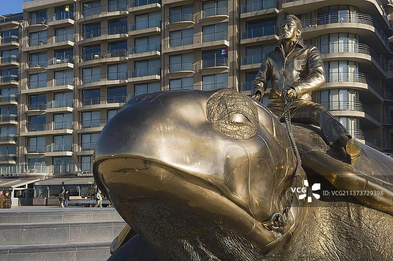 比利时西弗兰德斯纽波特海滩长廊上的海龟男人金色雕像图片素材