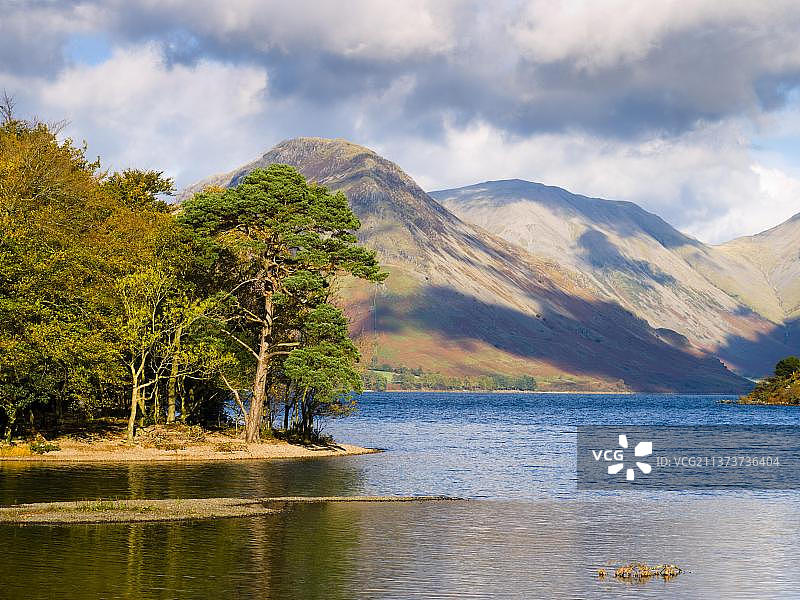 英国坎布里亚郡湖区国家公园瓦斯特沃特湖的低矮树木，远处是尤巴罗山和柯克费尔山图片素材