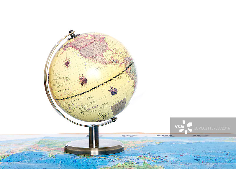 白背景前一个地球仪放在纸质地图上图片素材