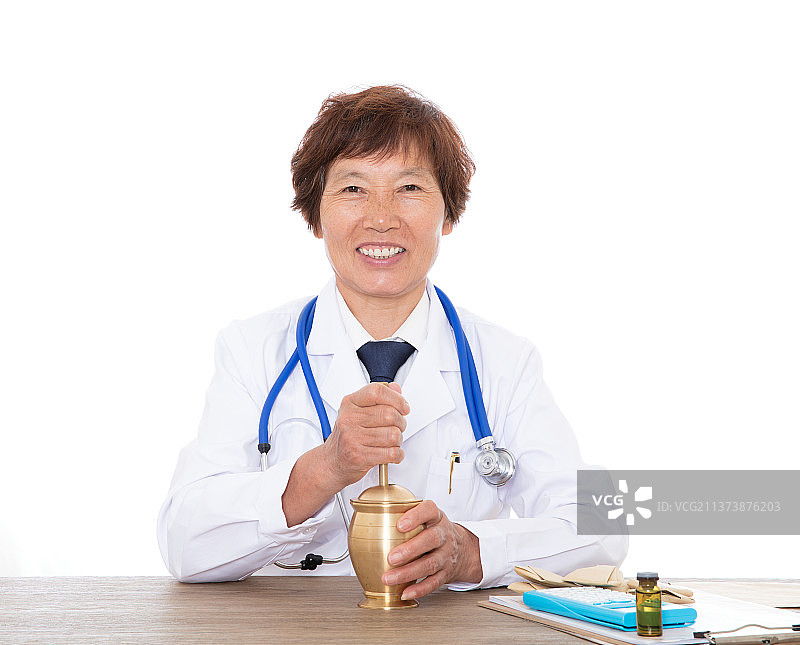 资深的中医药师微笑看着镜头在使用药臼捣药图片素材