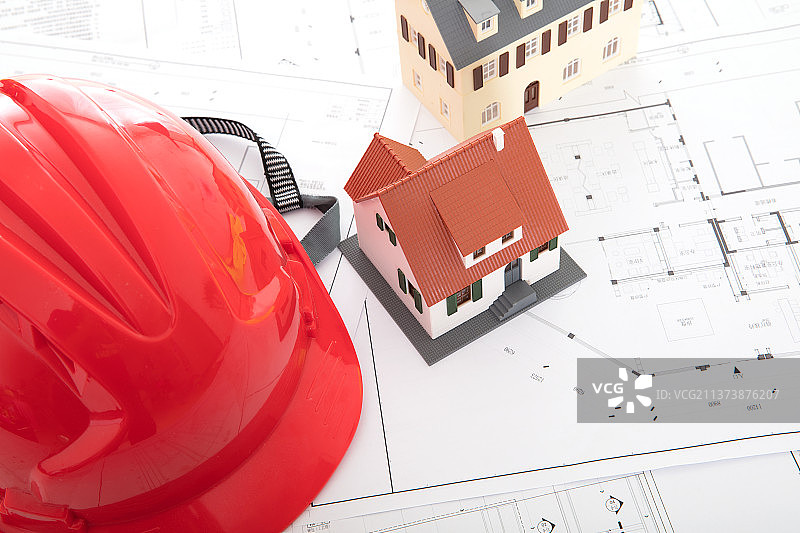图纸上的红色安全帽和两个小房子模型图片素材