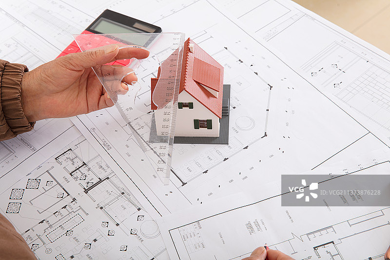 建筑设计师用尺子量着房子模型来分析图纸的精度图片素材