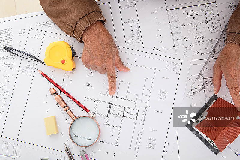 俯视拍摄设计师对比着房屋模型检查图纸图片素材