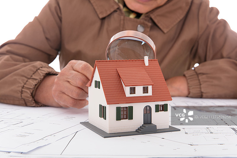 建筑设计师手持放大镜观察小房子模型图片素材