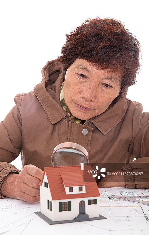 建筑设计师手持放大镜观察小房子模型图片素材