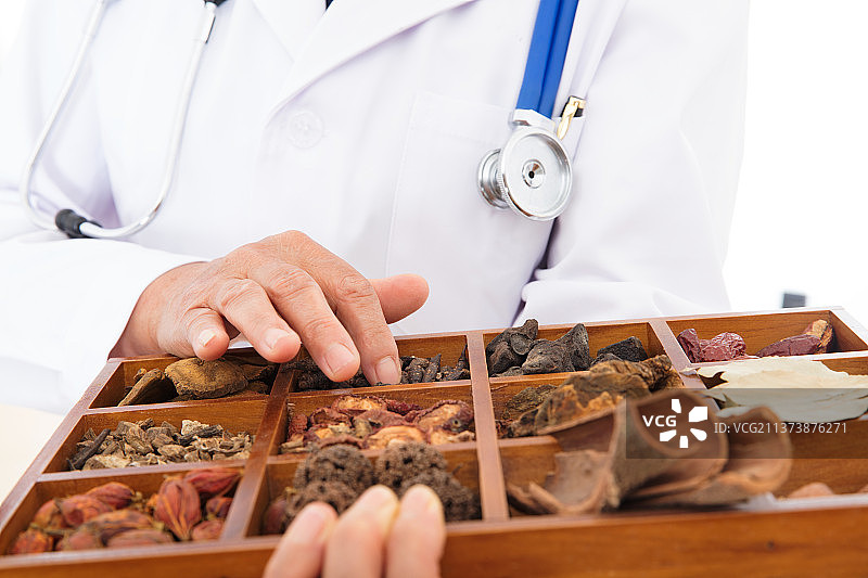 特写拍摄医生端着中药盒手在上面抚摸图片素材