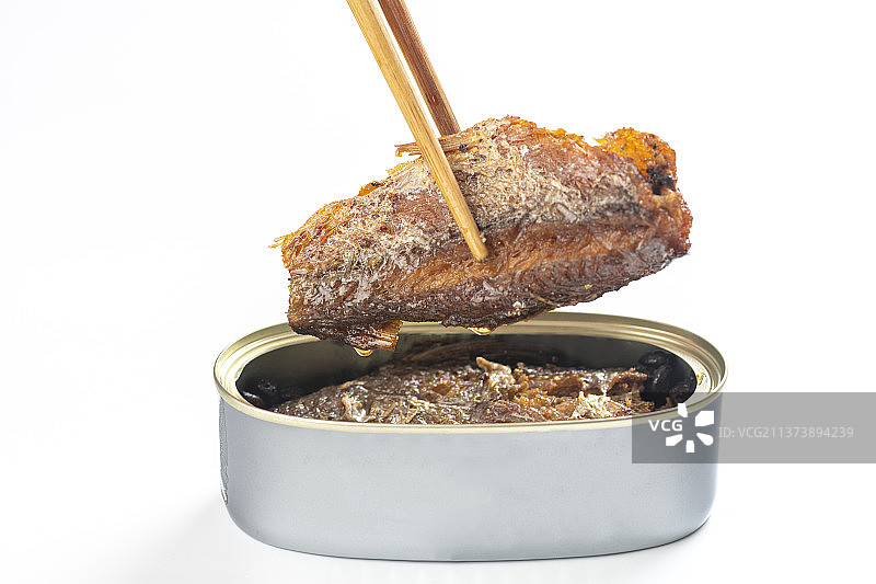 用筷子从罐头中夹起豆豉鲮鱼白色背景图片素材