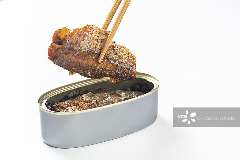 用筷子从罐头中夹起豆豉鲮鱼白色背景图片素材