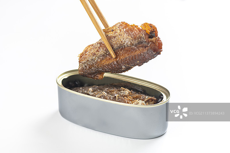 用筷子从罐头中夹起豆豉鲮鱼白色背景图片素材