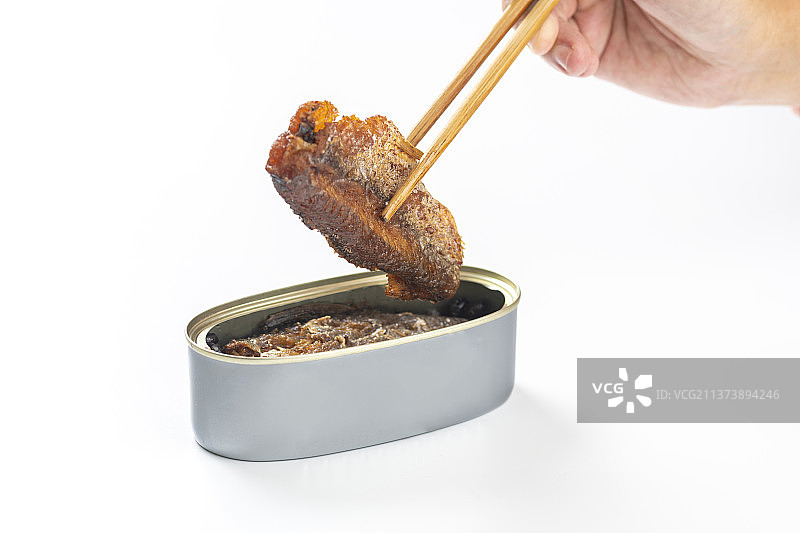 用筷子从罐头中夹起豆豉鲮鱼白色背景图片素材