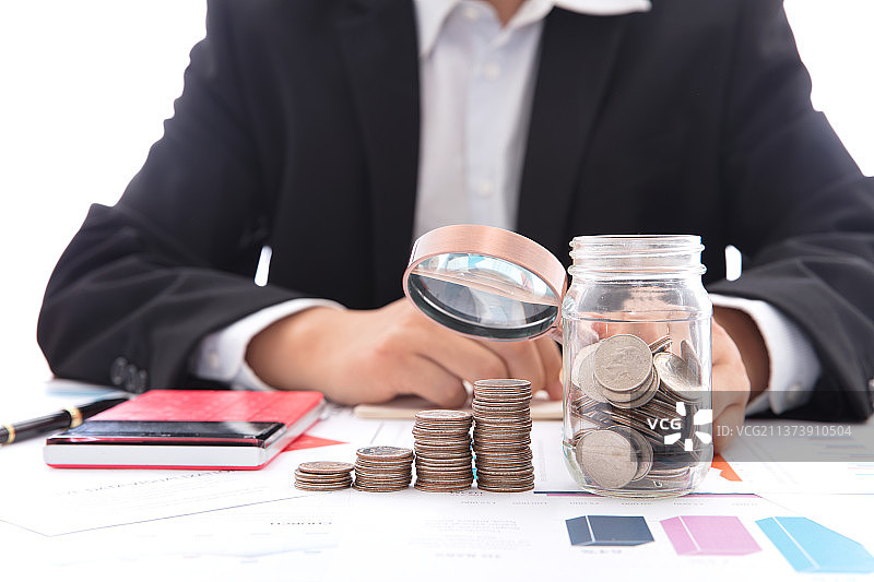 商业投资者手拿放大镜观察一排美元硬币图片素材