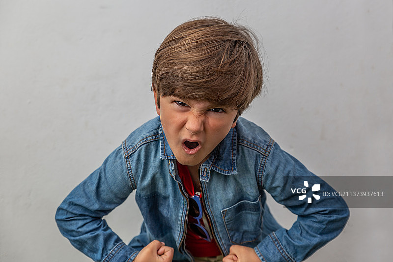 穿着蓝色夹克的非常生气的男孩特写图片素材