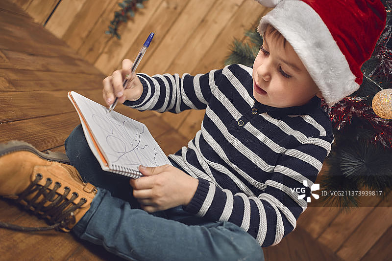 在西班牙的家中坐在桌旁给圣诞老人写信的男孩图片素材