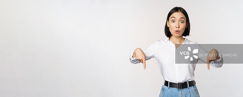 年轻的亚洲女人用手指朝下指着并微笑图片素材