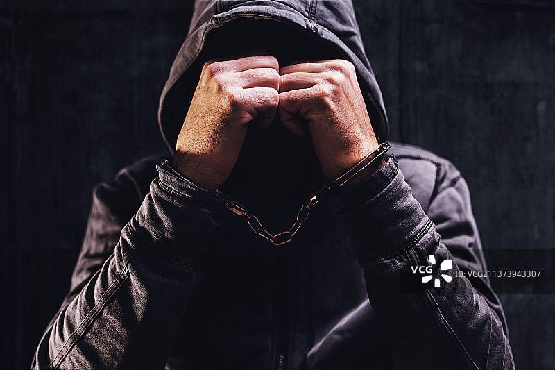 戴着手铐，遮住脸的被捕罪犯，塞尔维亚图片素材