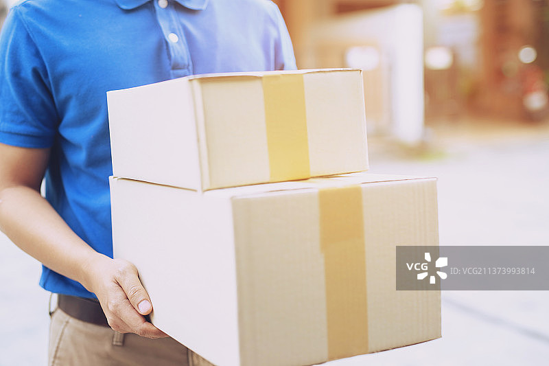 包裹派送员，拿着包裹，派送员拿着纸板箱的中间部分图片素材