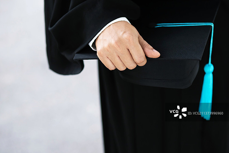 年轻男性毕业背影照，手持毕业帽的男子图片素材