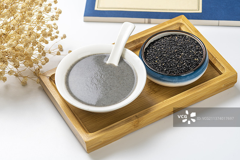 一碗黑芝麻糊和一盘黑芝麻特写白色背景图片素材