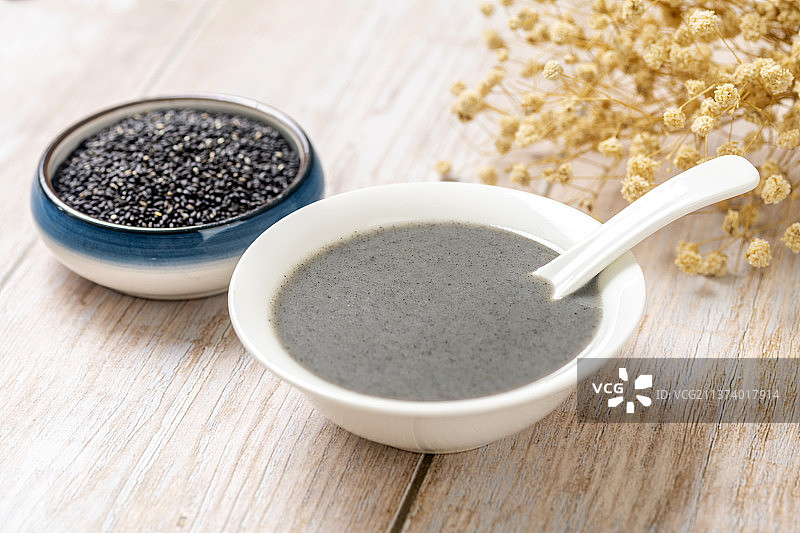 一碗黑芝麻糊和一盘黑芝麻特写木桌面背景图片素材