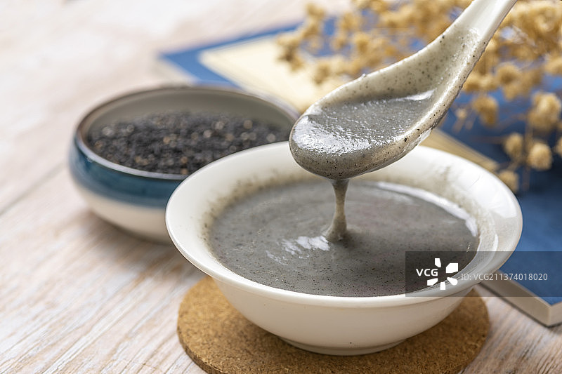用勺盛起黑芝麻糊特写木桌面背景图片素材