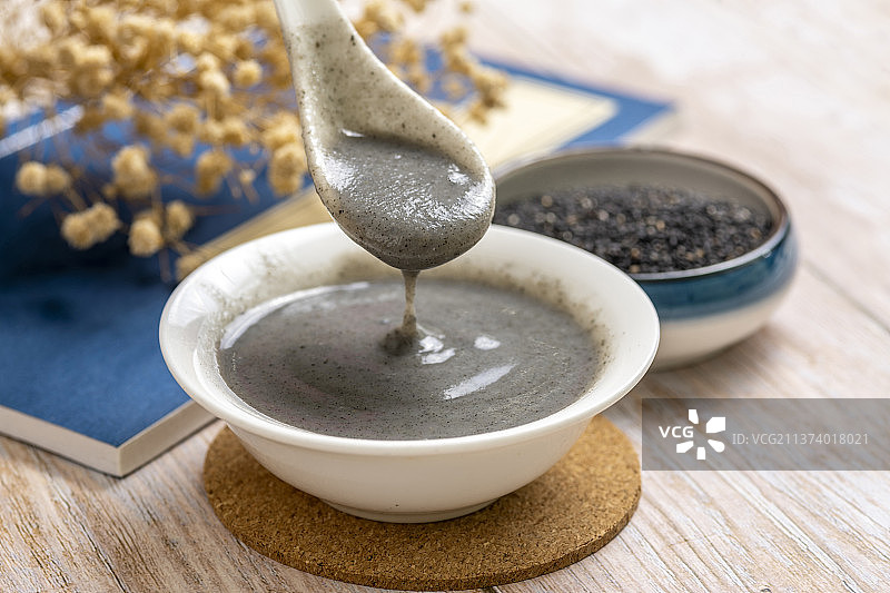 用勺盛起黑芝麻糊特写木桌面背景图片素材