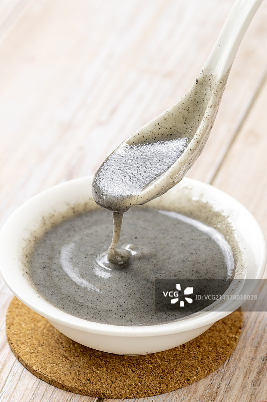 用勺盛起黑芝麻糊特写木桌面背景图片素材