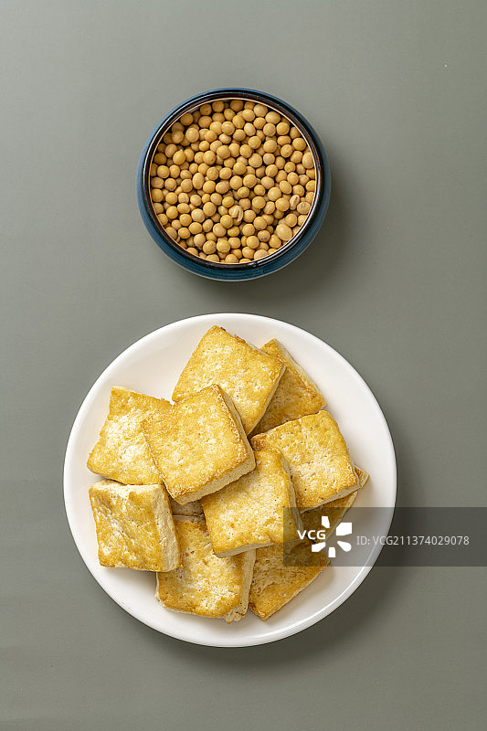 一盘炸豆腐与一盘黄豆特写灰色背景图片素材