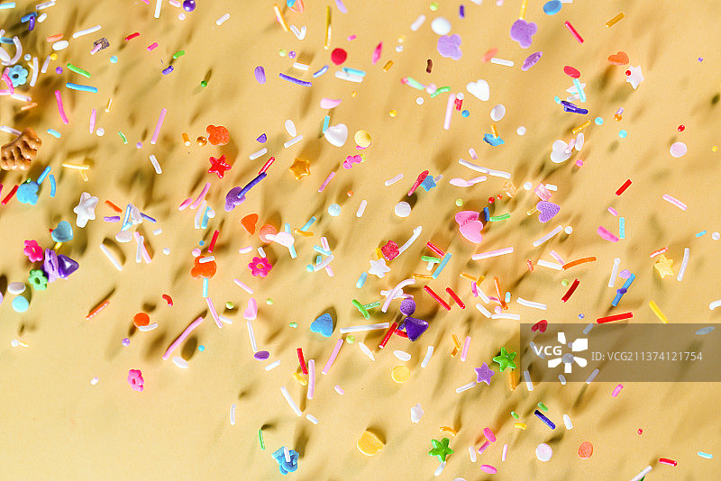 彩色各类糖果掉落在黄色背景上棚拍创意图图片素材