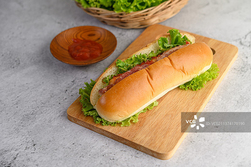 木制砧板上的热狗配生菜和番茄酱图片素材