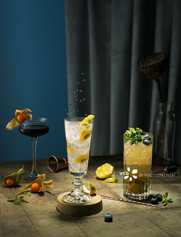 绿色背景上的各种鸡尾酒，含苏打水、杜松子酒、猕猴桃和浆果图片素材