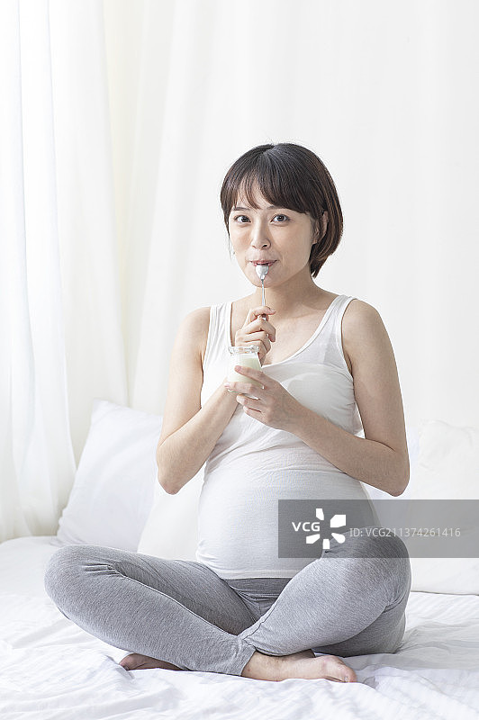 孕妇盘腿坐着吃优格图片素材