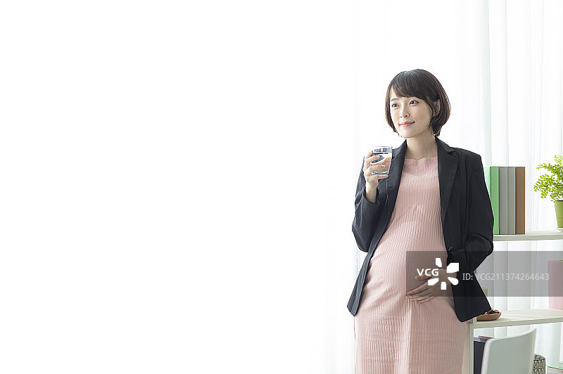 孕妇拿着杯子手摸肚子站着图片素材