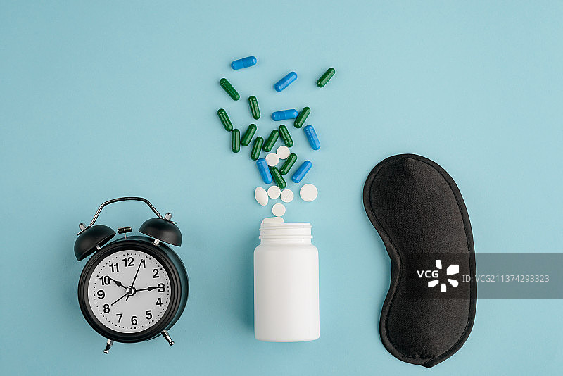 蓝色背景上的闹钟、药丸和眼罩俯视图图片素材
