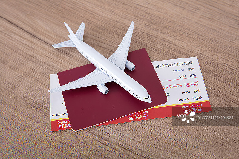 一个白色的小飞机模型在夹着飞机票的护照上图片素材