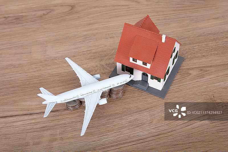放在美元硬币上的飞机模型机头对着小房子模型图片素材